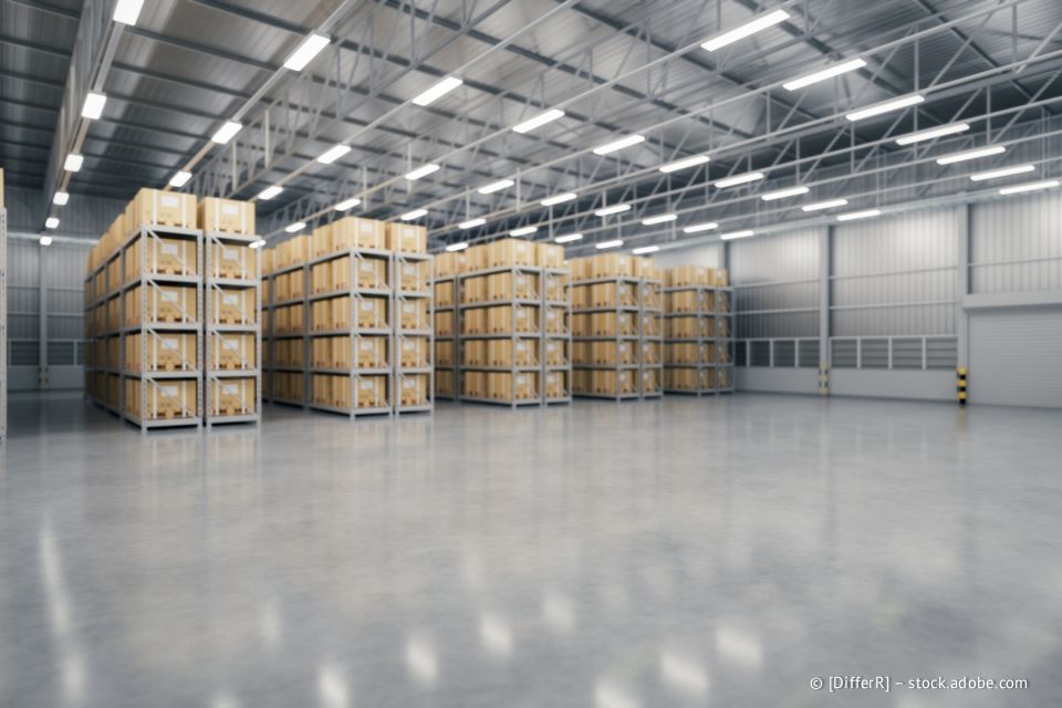 Lagerhalleninnenraum mit Reihen gestapelter Kartons auf Metallregalen, Betonboden.