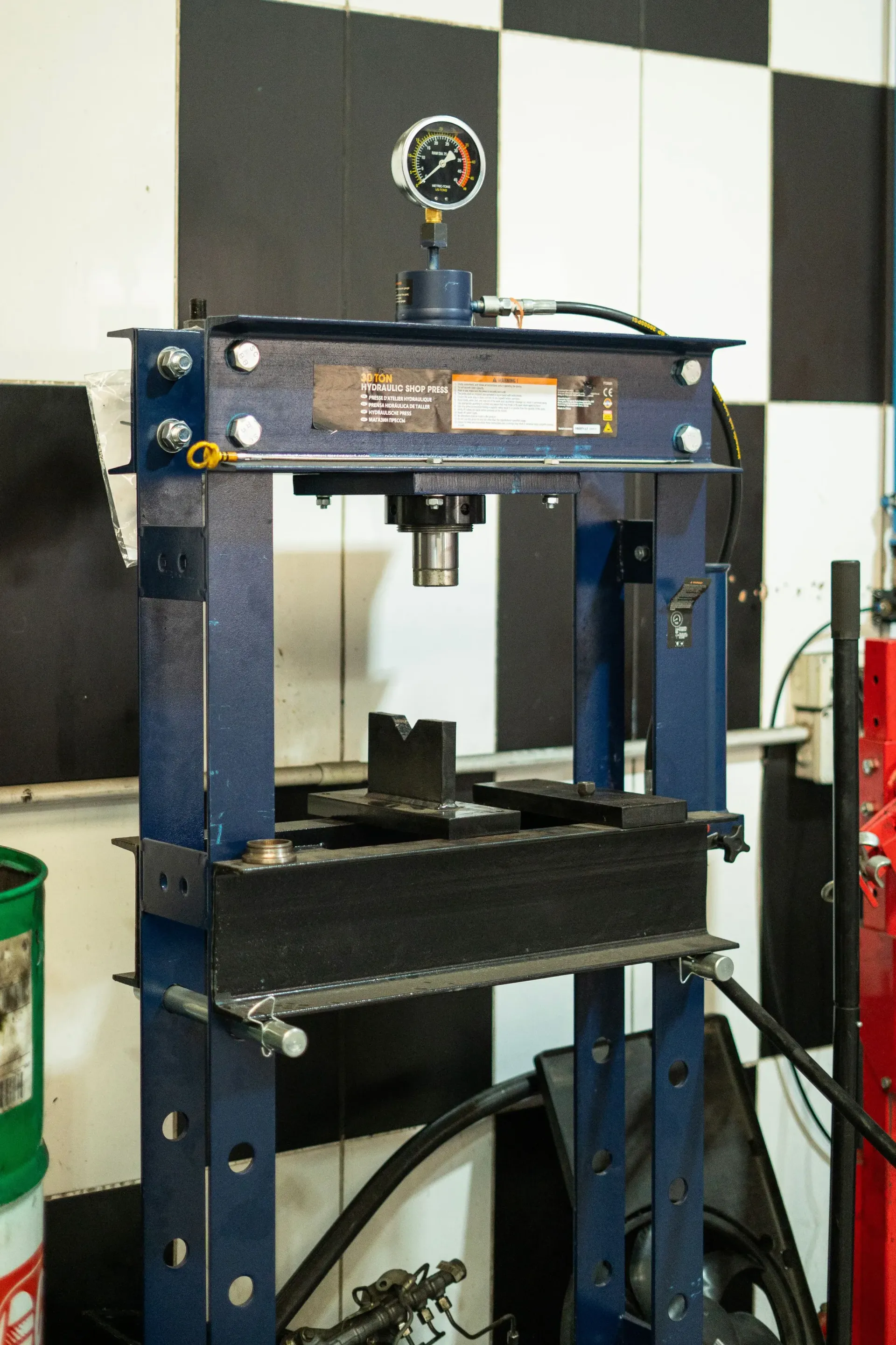 Prensa hidráulica azul en un taller, utilizada para dar forma o conformar objetos metálicos.