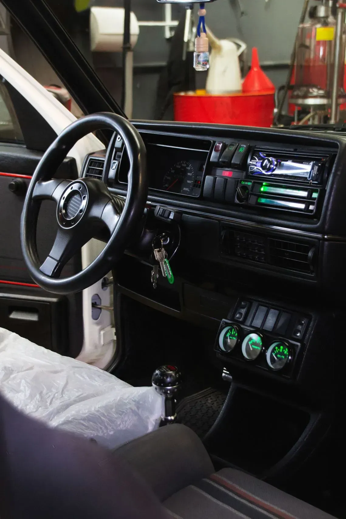 Interior del coche en color negro, con volante, salpicadero y palanca de cambios. Indicadores con iluminación verde.