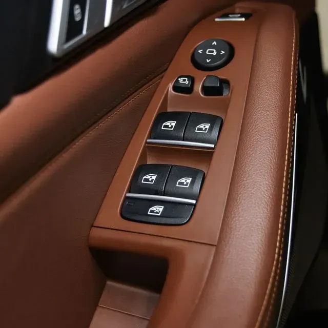 Panel de puerta de coche marrón con mandos de ventana.