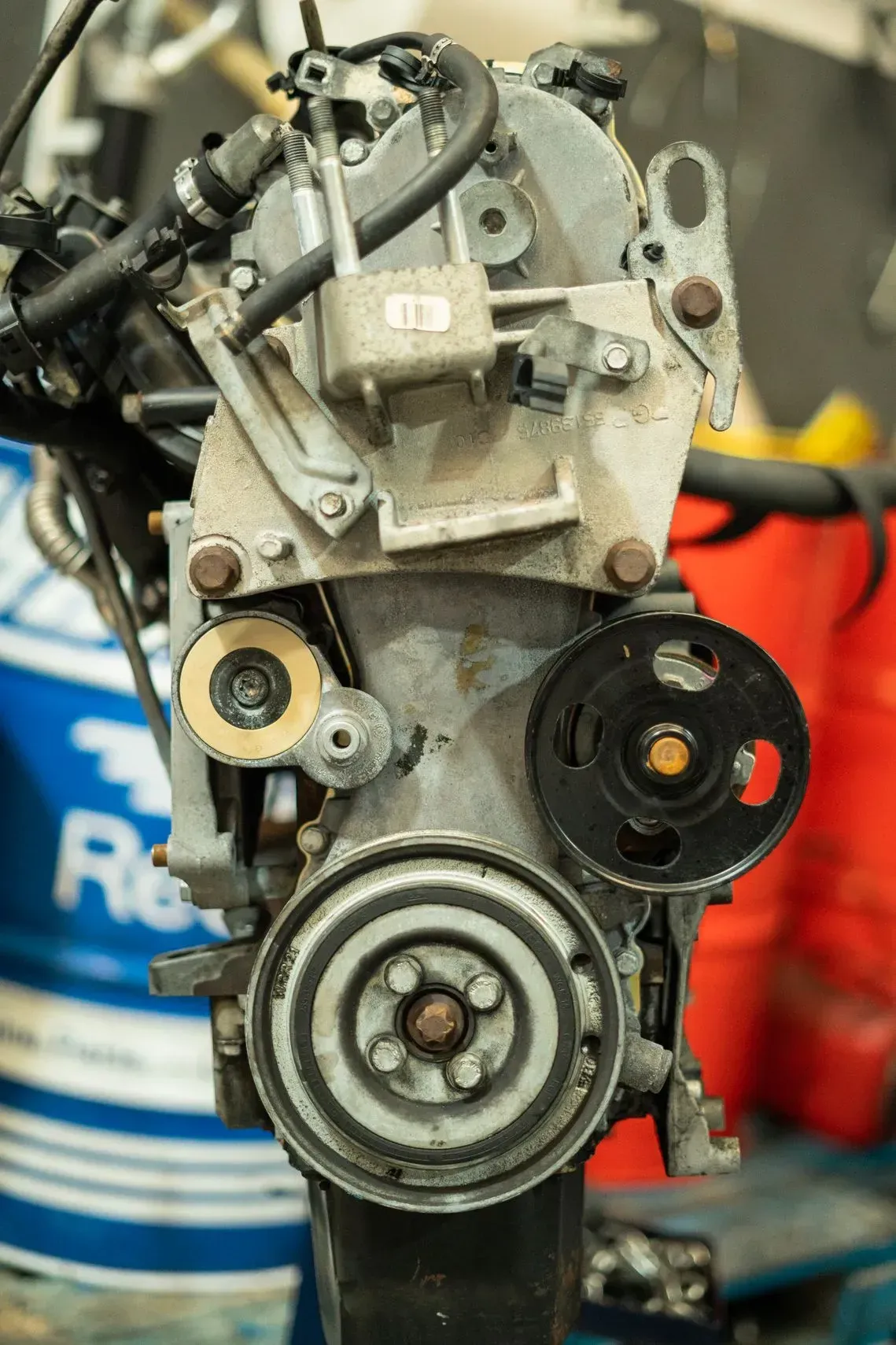 Motor con correas y poleas, de metal gris, visto de lado, en un taller.