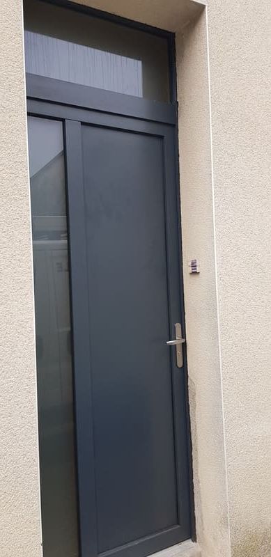 Porte d'entrée noire avec mur en crépis