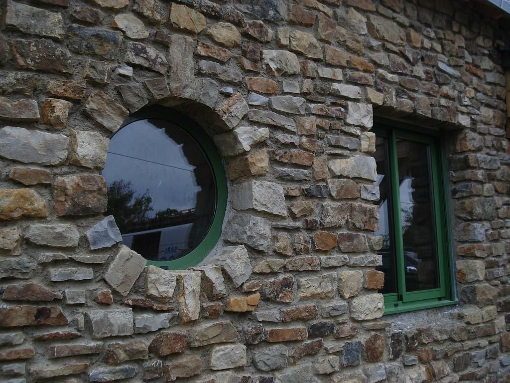 Fenêtres de plusieurs formes sur une façade en pierre