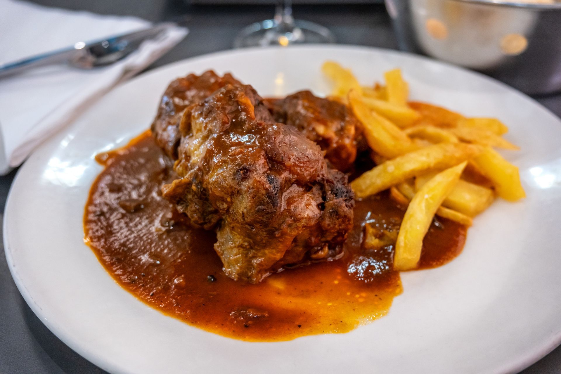 Plato de carne estofada en salsa con patatas fritas.