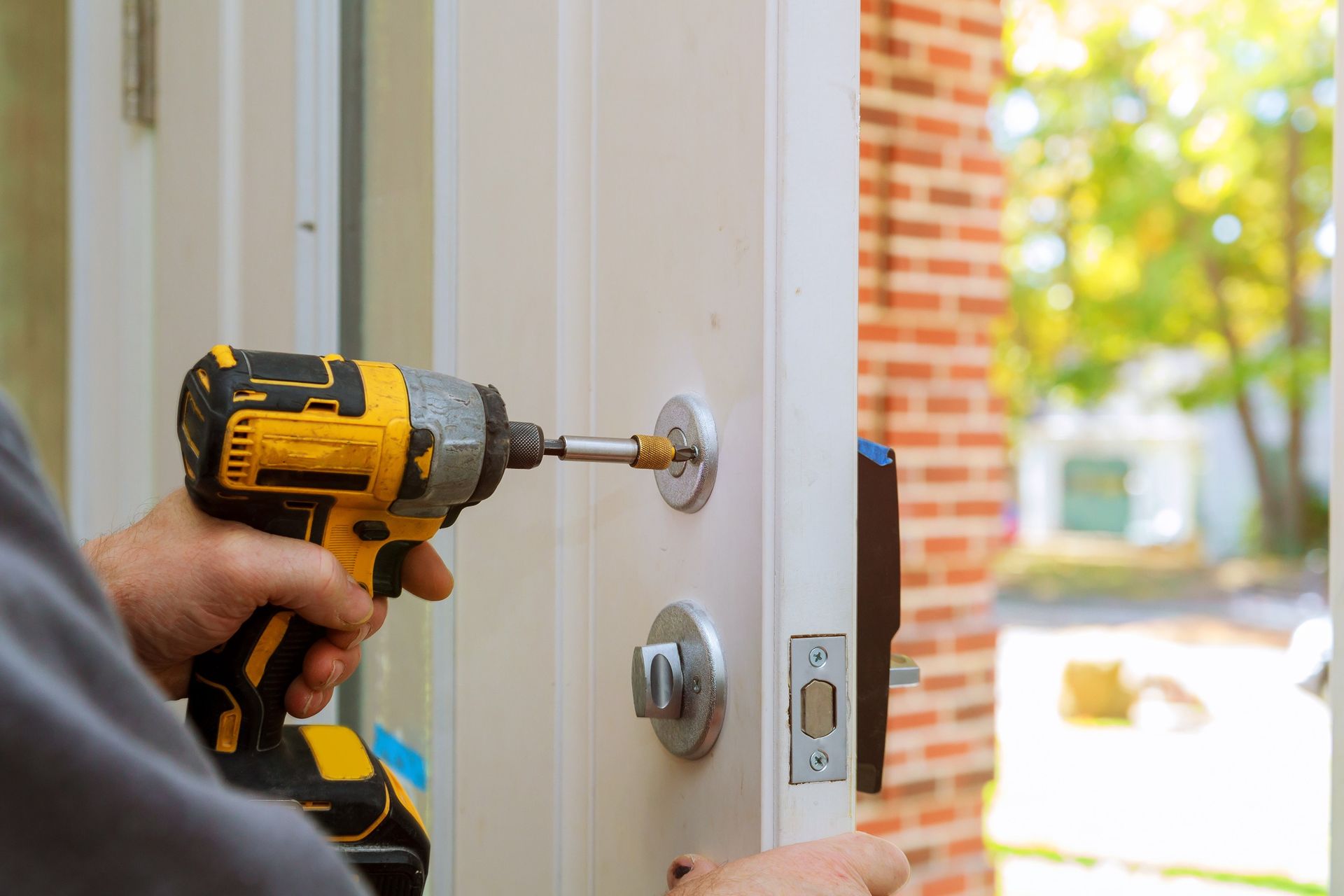 Un hombre está usando un taladro para arreglar una cerradura de puerta.