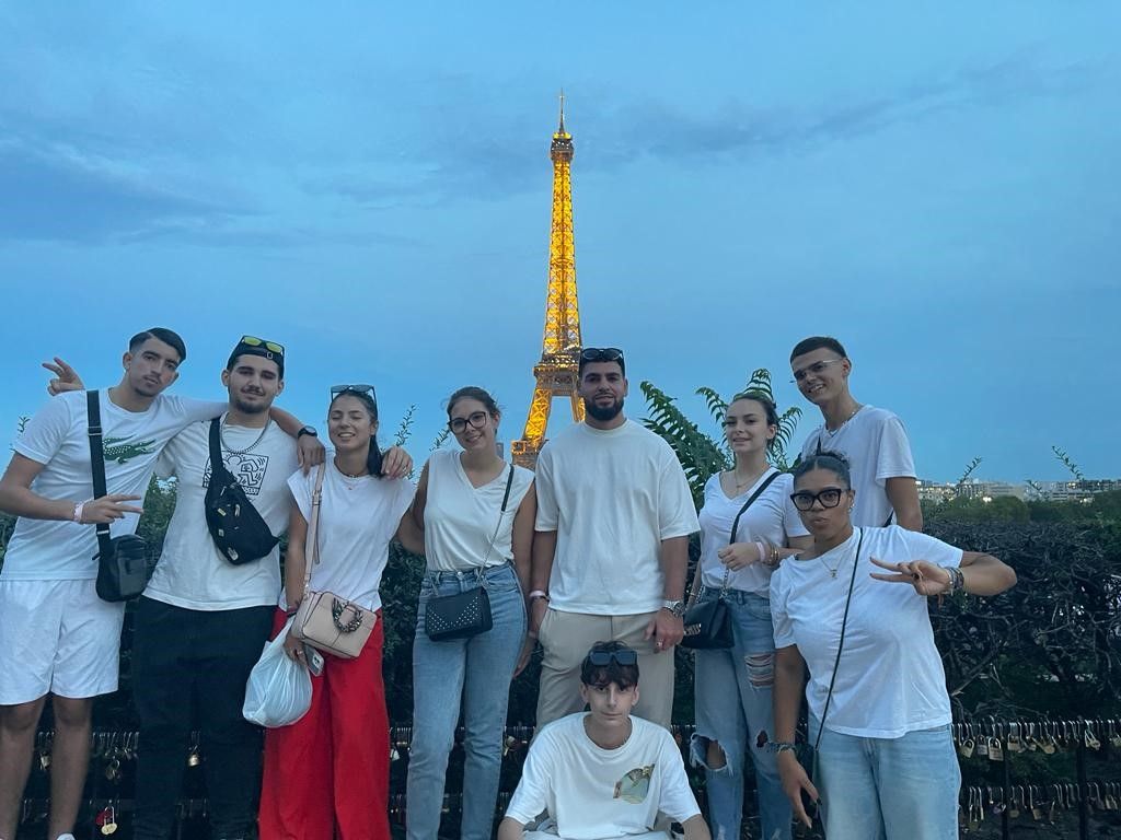 Groupe posant au crépuscule avec la tour Eiffel illuminée en arrière-plan