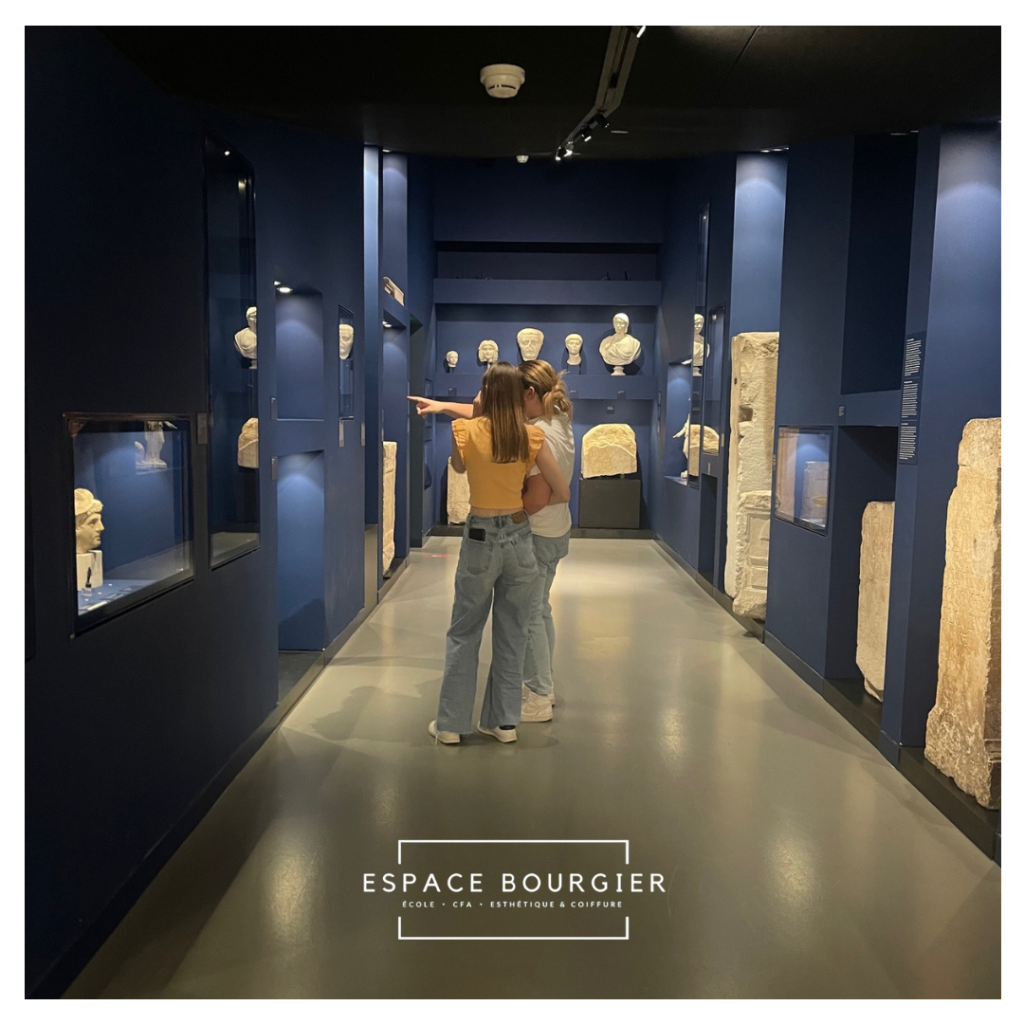 Galerie de musée aux murs et expositions bleus, deux personnes debout au centre.