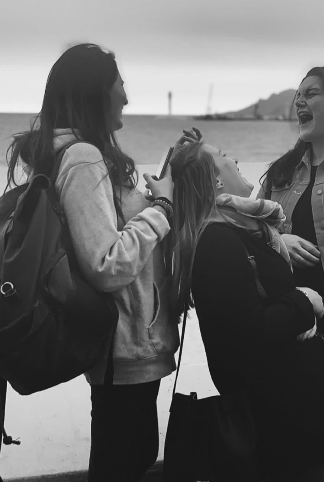 Trois personnes debout au bord de l'eau, souriant et discutant sur une plage