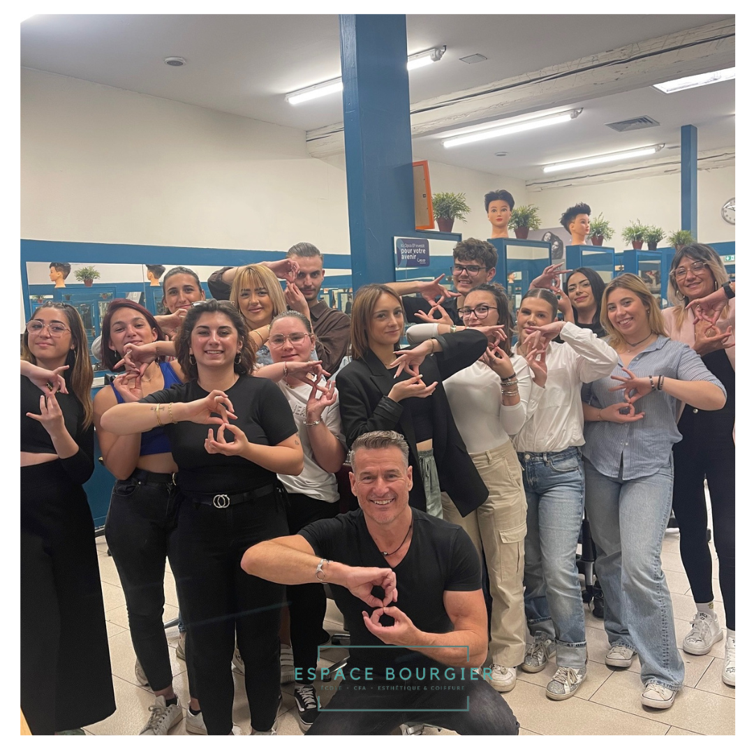 Un groupe de personnes dans une salle de classe fait des gestes de la main et sourit à la caméra.