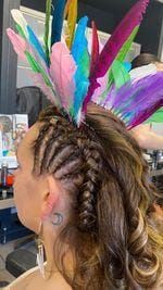 Personne avec des tresses et une coiffe de plumes colorées dans un salon de coiffure