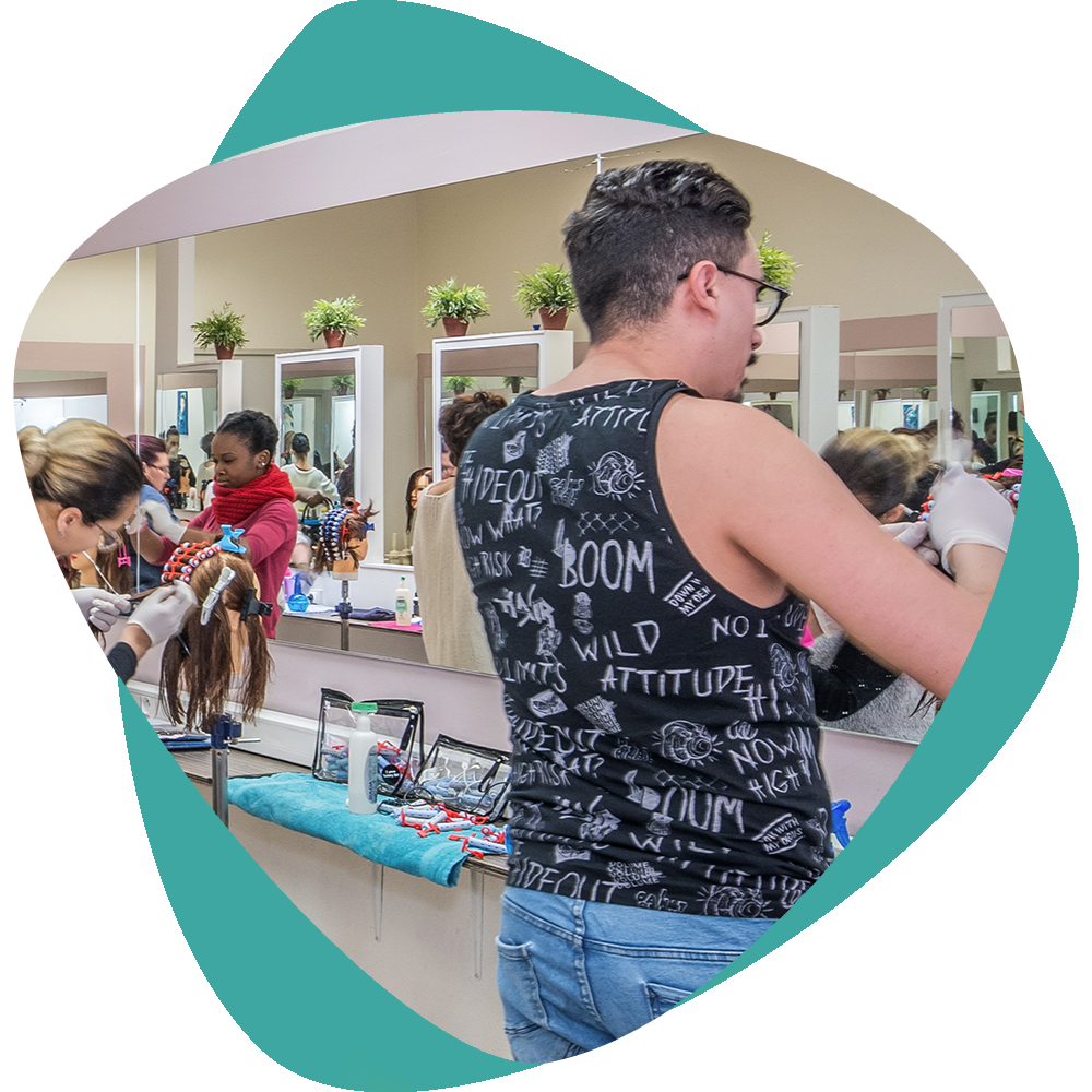 Une personne vêtue d'un débardeur noir se tient devant le comptoir d'un salon de coiffure, avec des produits capillaires et un miroir derrière elle.