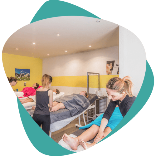 Séance de massage dans une salle de clinique lumineuse, avec deux thérapeutes traitant des clients sur des tables de massage.