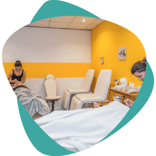 Salle de massage lumineuse avec chaises beiges, murs jaunes, plafond turquoise et une personne assise à gauche.