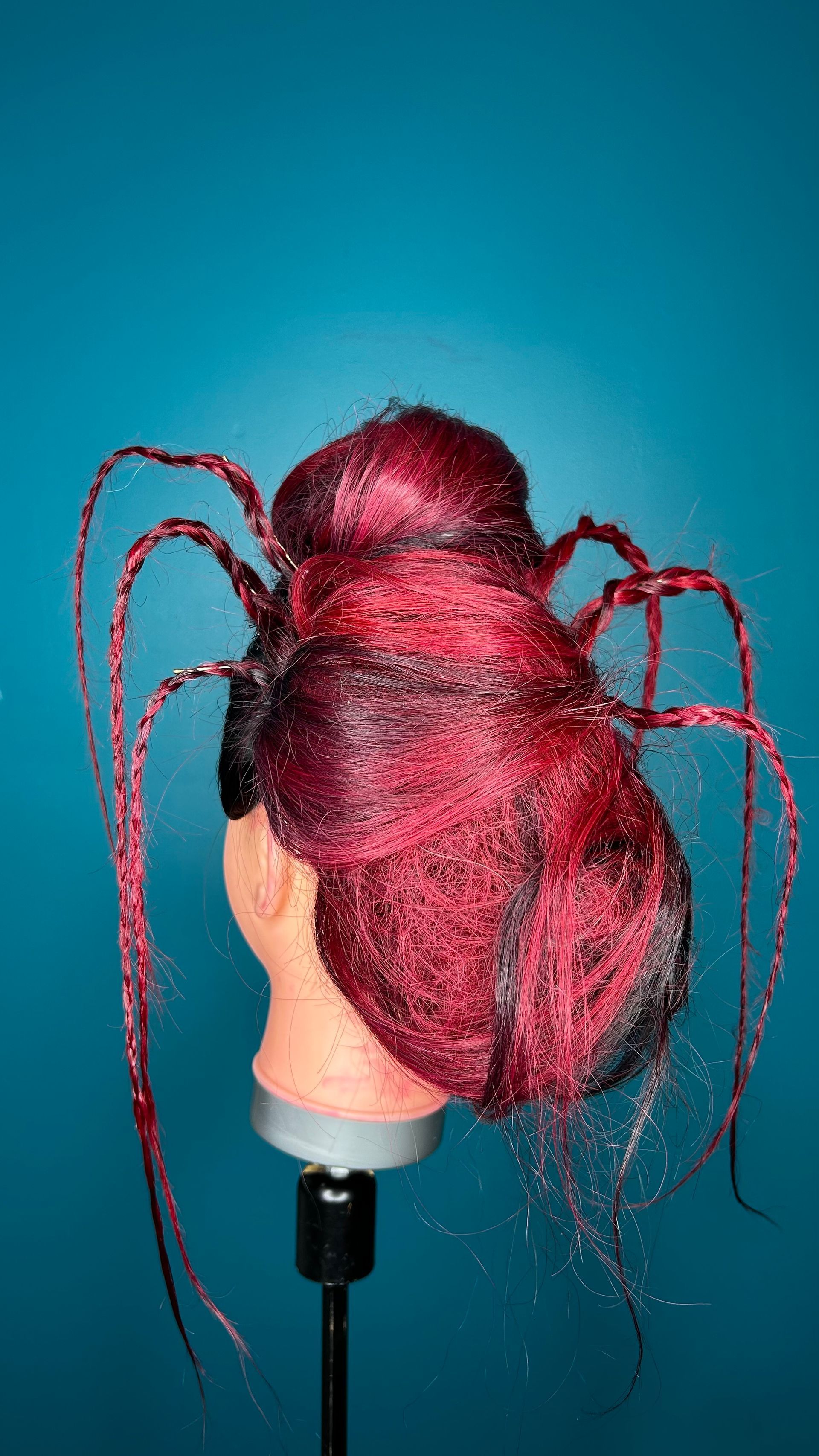 Tête de mannequin avec une perruque rose vif coiffée en chignon sur fond bleu