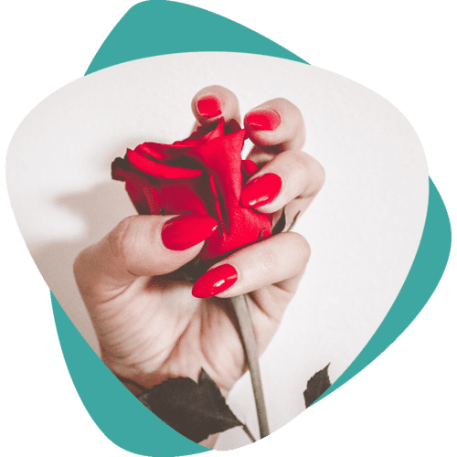 Main tenant une rose rouge, ongles vernis en rouge, sur fond blanc et turquoise