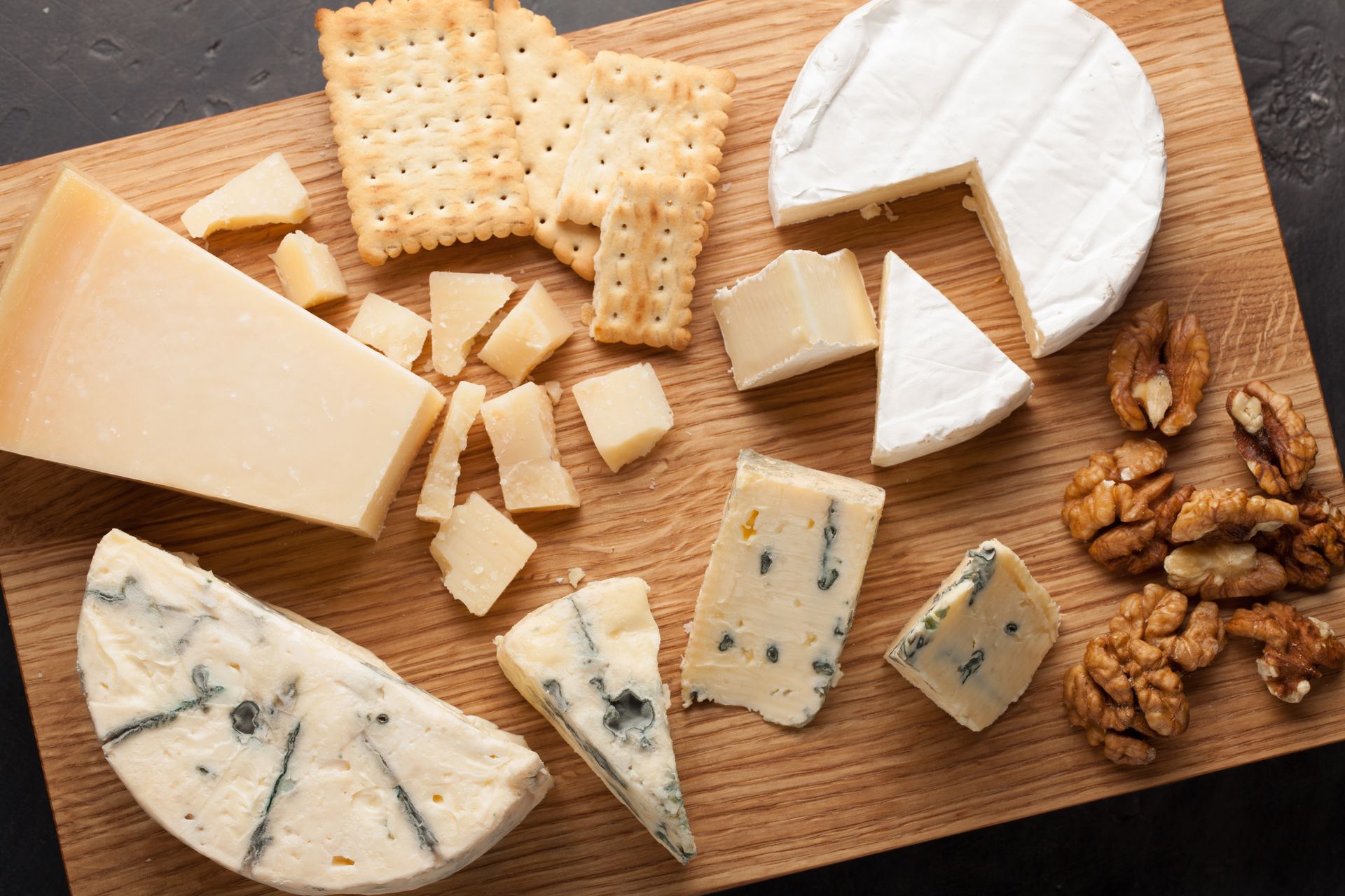 Hay muchos tipos diferentes de queso y galletas en la tabla de cortar.