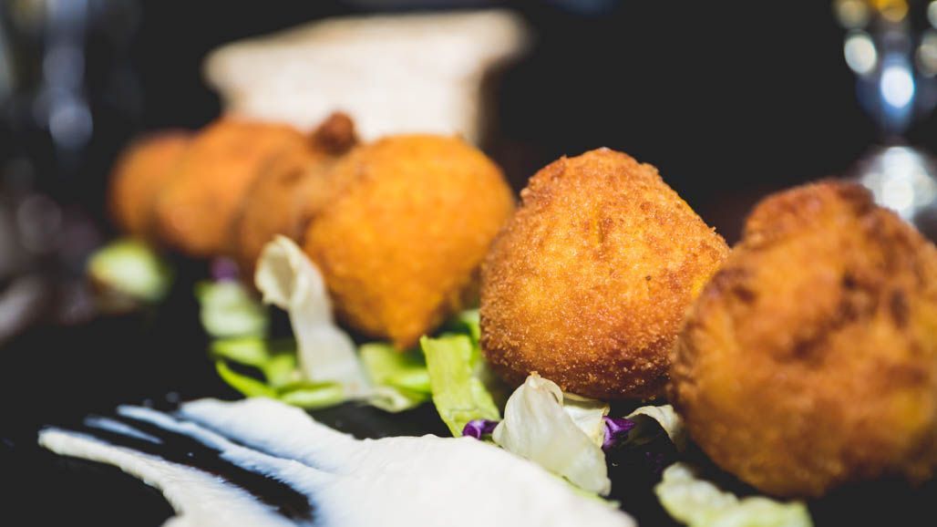 Un primer plano de comida frita en un plato con lechuga y salsa.