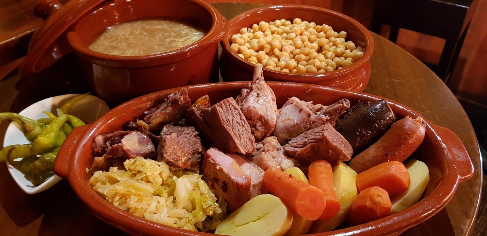 Un plato de comida con carne, verduras y frijoles en una mesa.