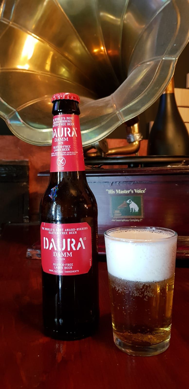 Una botella de cerveza y un vaso de cerveza están sobre una mesa.