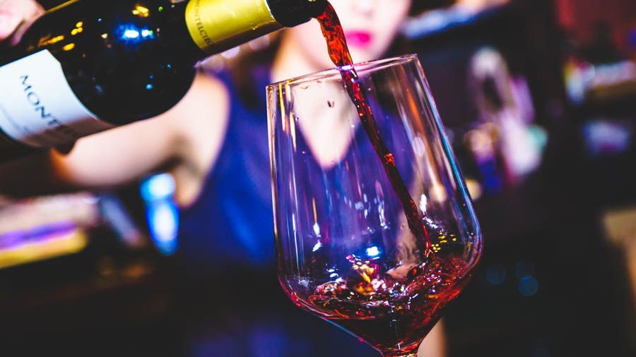 Una mujer está vertiendo vino tinto en una copa.