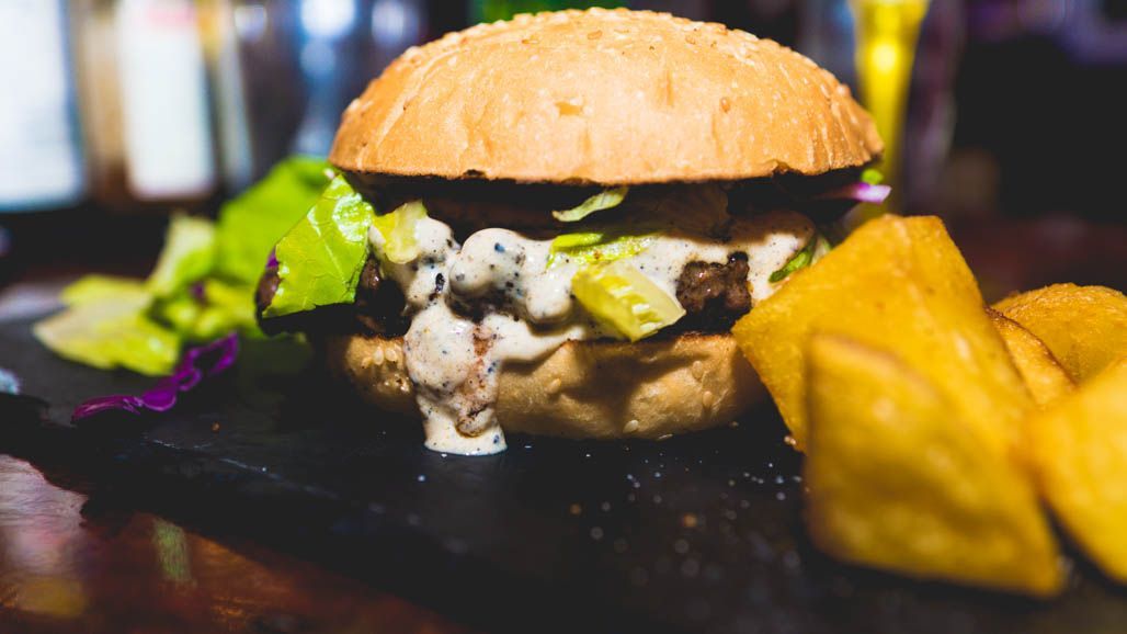 Un primer plano de una hamburguesa y papas fritas en una mesa.