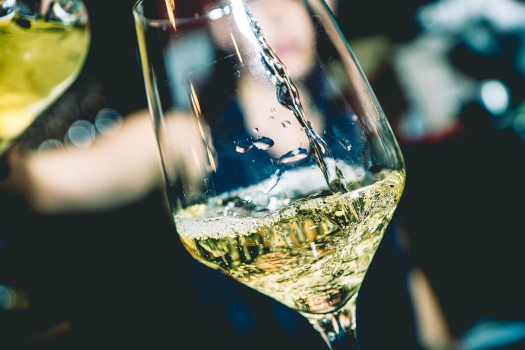 Un primer plano de una persona vertiendo vino en una copa.