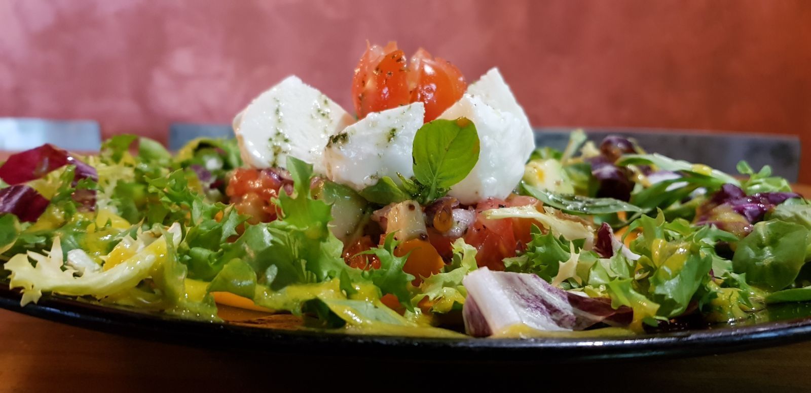 Un primer plano de una ensalada en un plato sobre una mesa.