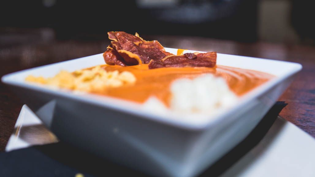 Un tazón de sopa con tocino y queso encima.