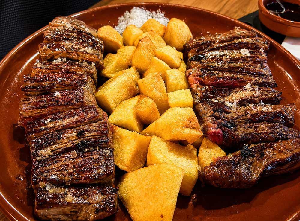 Filete a la parrilla con patatas gajo doradas en un plato marrón.