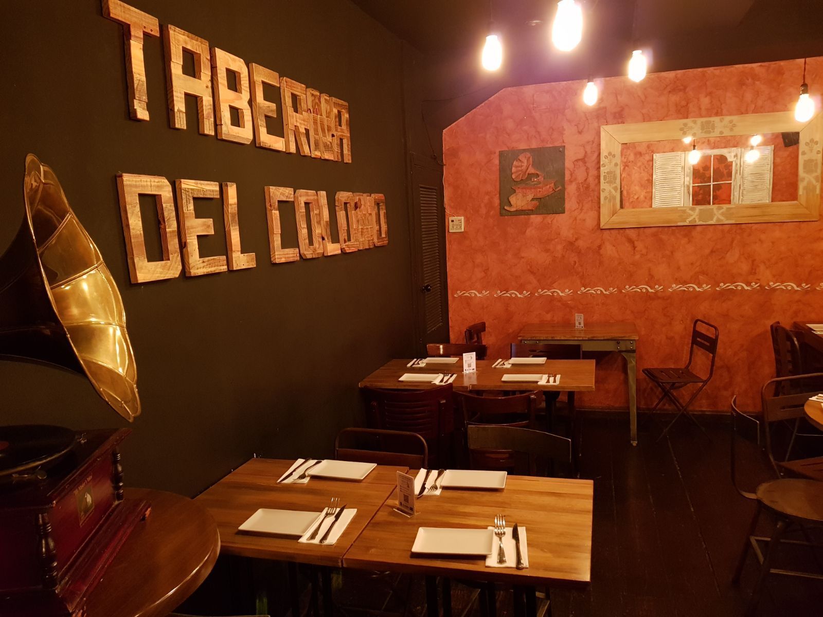 Un restaurante con mesas y sillas y una pared que dice taberna del color