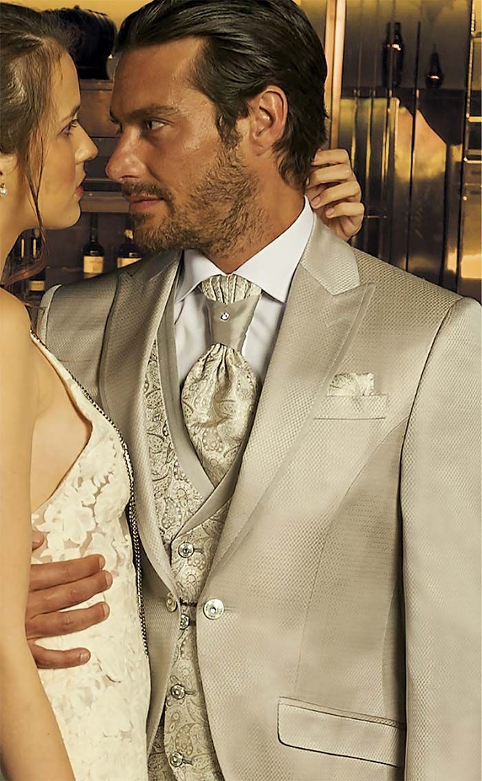 Una parella vestida de blanc d’etiqueta s’abraça en un casament o un esdeveniment, cara a cara i molt a prop.