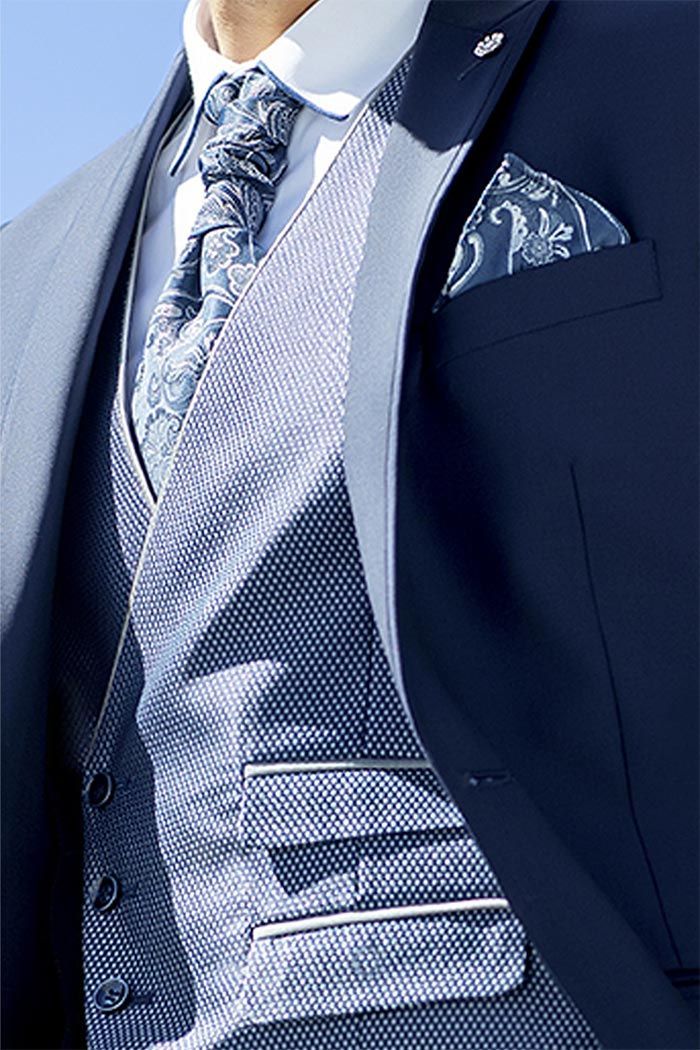 Primer pla d’una americana blau marí amb una corbata estampada i un mocador de butxaca.