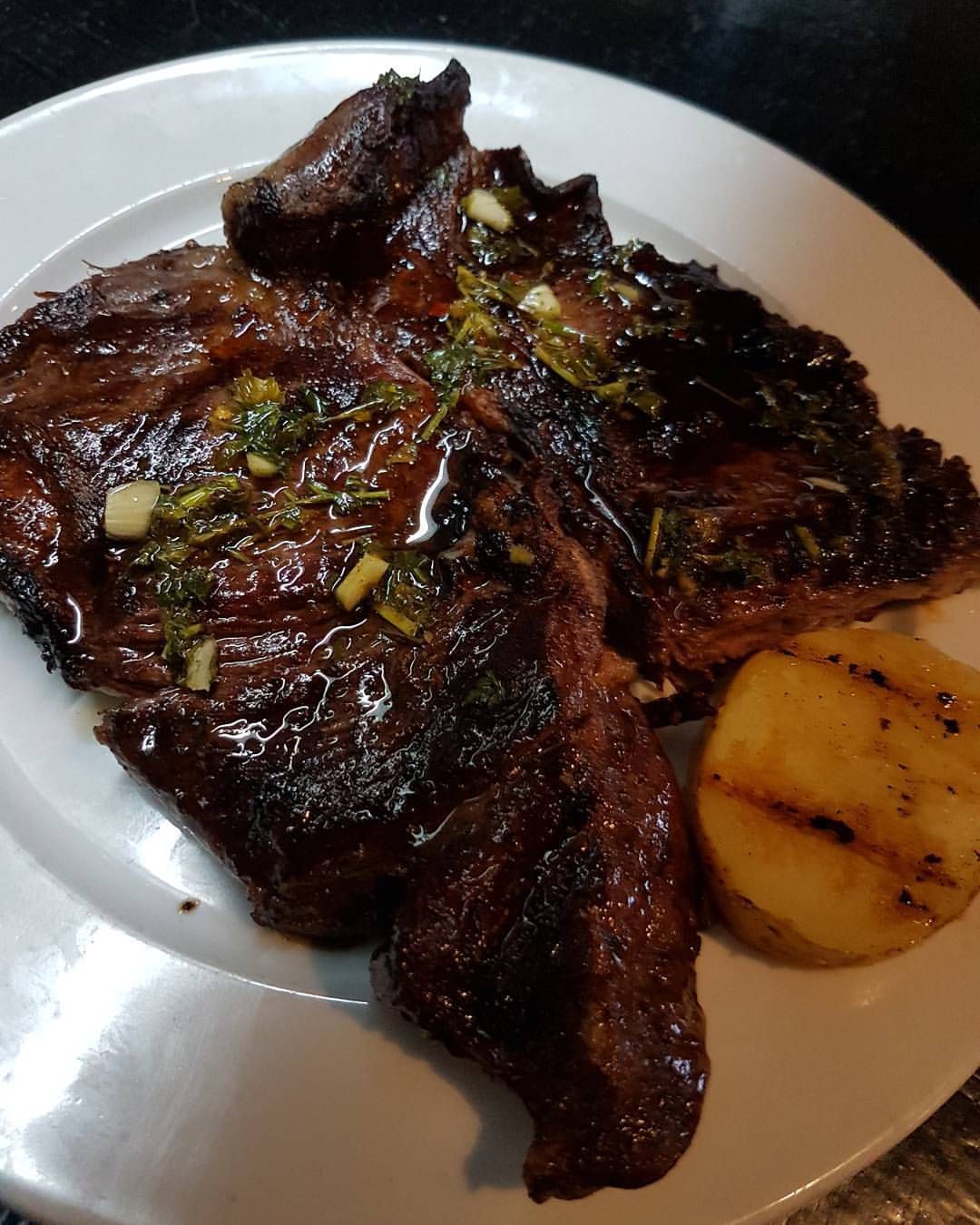 Un plato blanco cubierto con un filete y patatas.