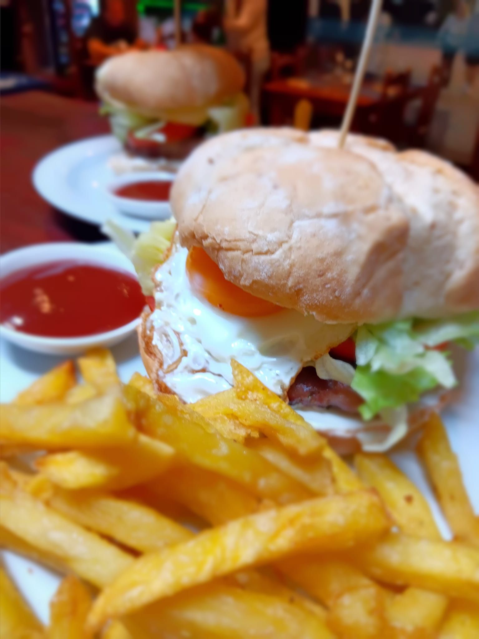 Un primer plano de una hamburguesa y papas fritas en un plato.