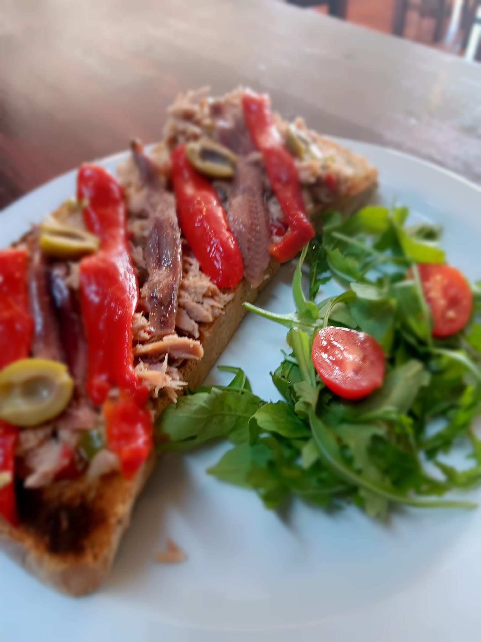 Un plato blanco cubierto con un sándwich y una ensalada.