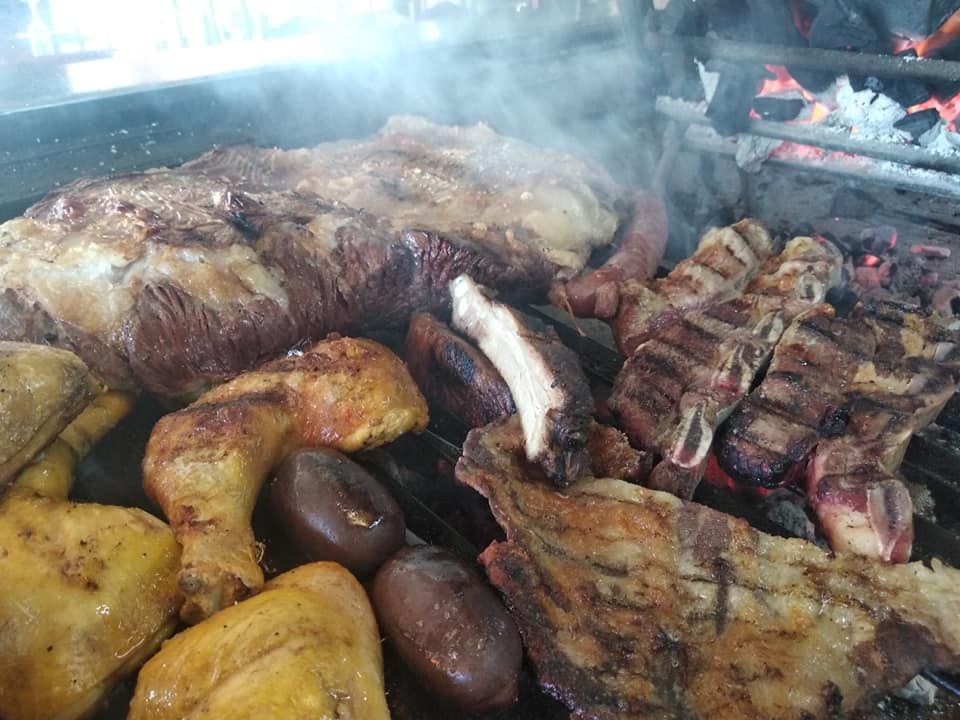 Un montón de carne se está cocinando en una parrilla.