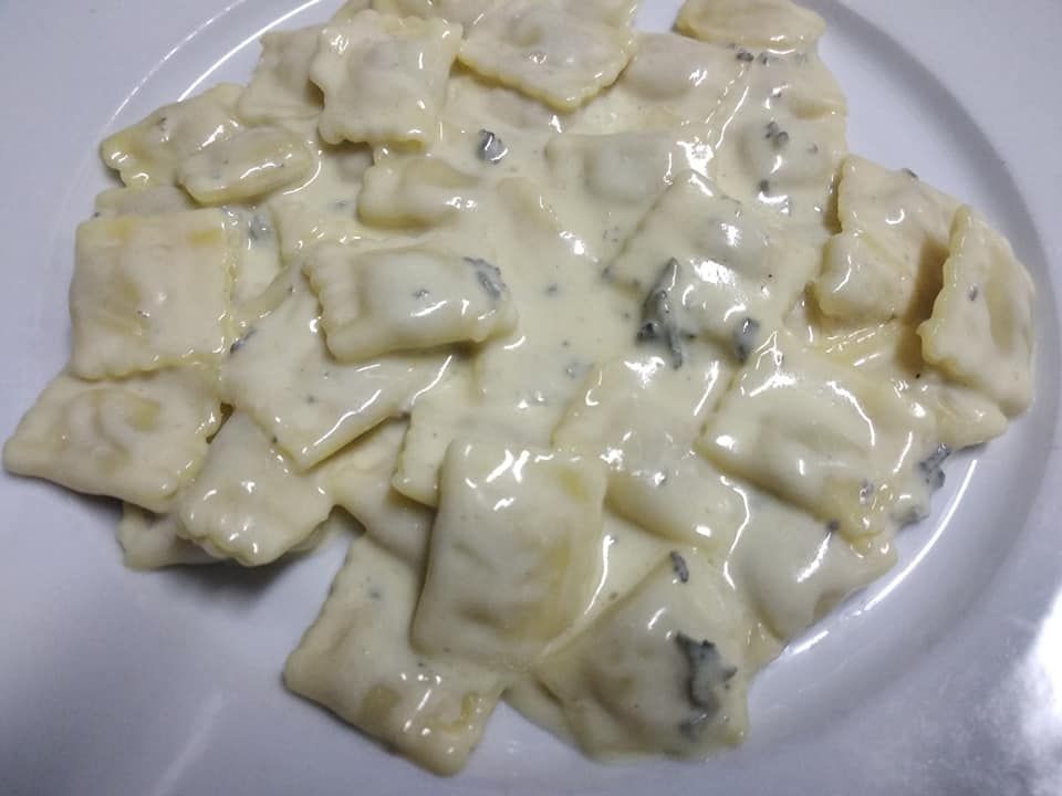Un plato blanco cubierto con ravioles en una salsa cremosa