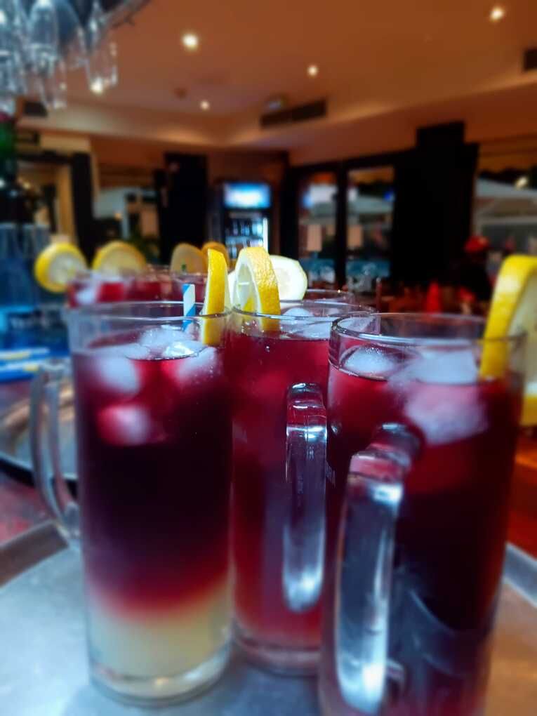 Una fila de tazas llenas de líquido rojo y hielo.
