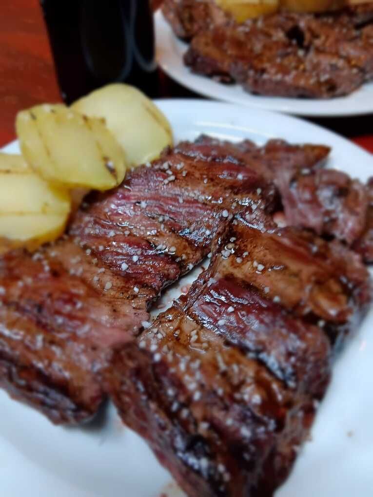 Un primer plano de un plato de carne y patatas sobre una mesa.