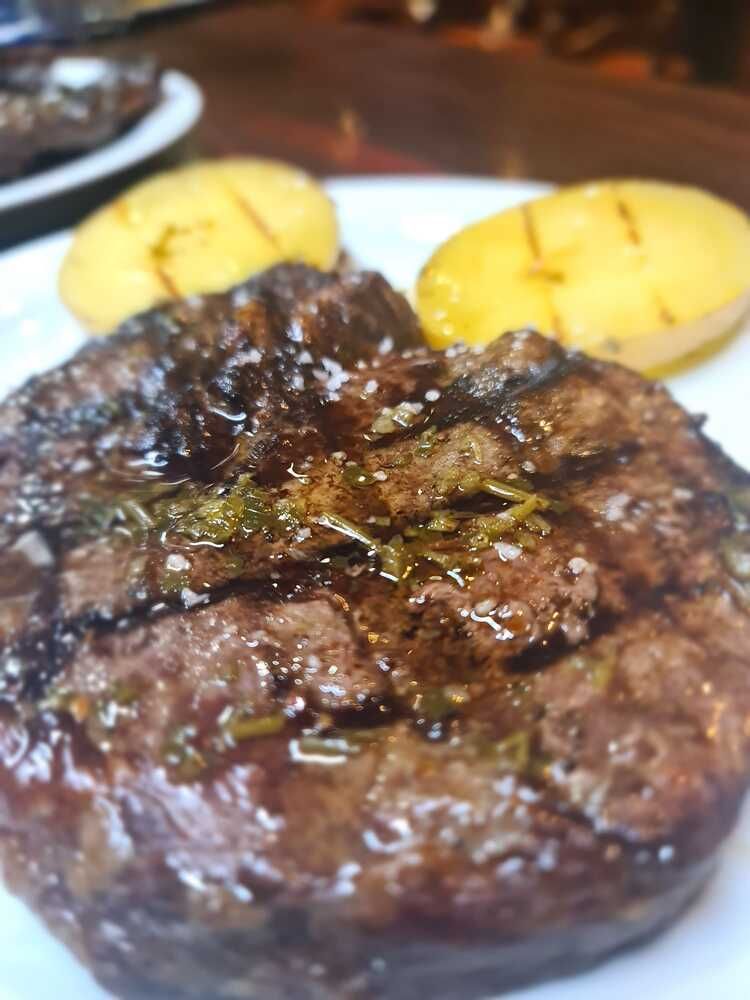 Un primer plano de un filete en un plato con patatas.