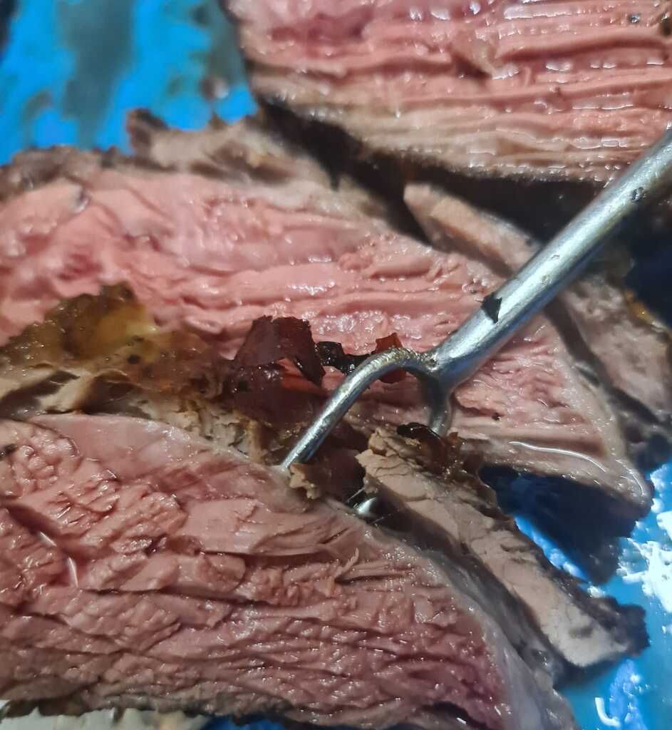 Un primer plano de un trozo de carne con un tenedor sobresaliendo de él.