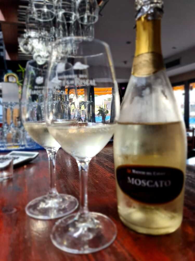 Una botella de vino moscato junto a dos copas