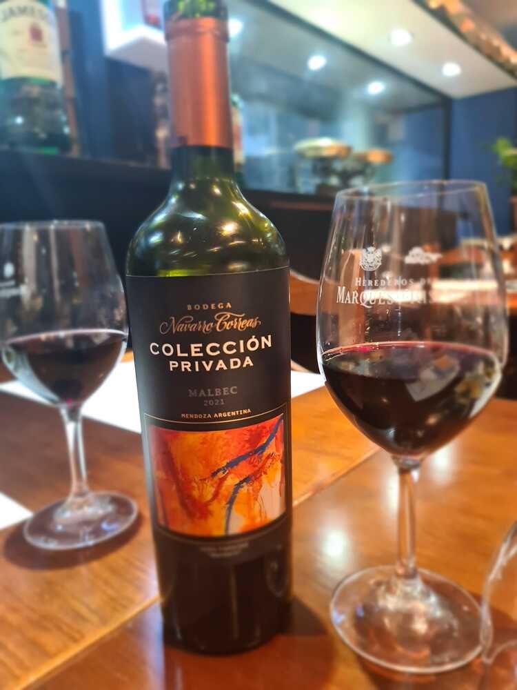 Una botella de vino está sobre una mesa al lado de dos copas de vino.