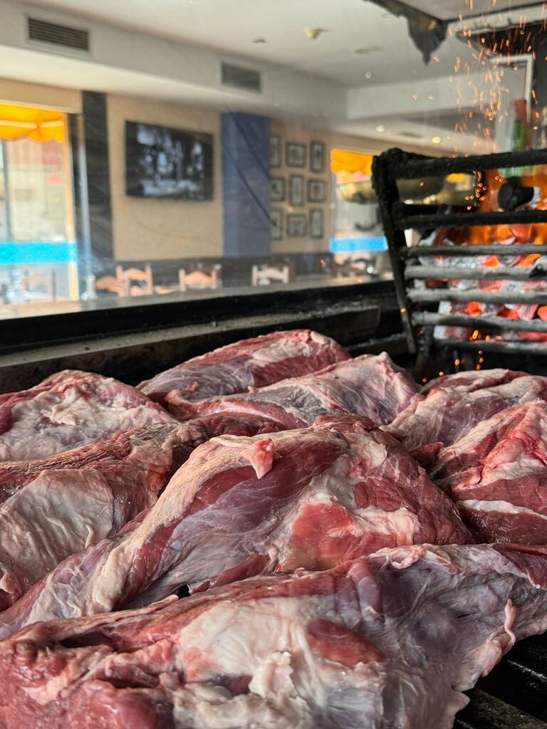 Una pila de carne cruda está encima de una parrilla.