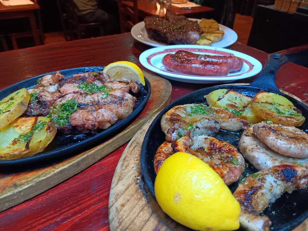 Una mesa cubierta con platos de comida que incluían salchichas y patatas.