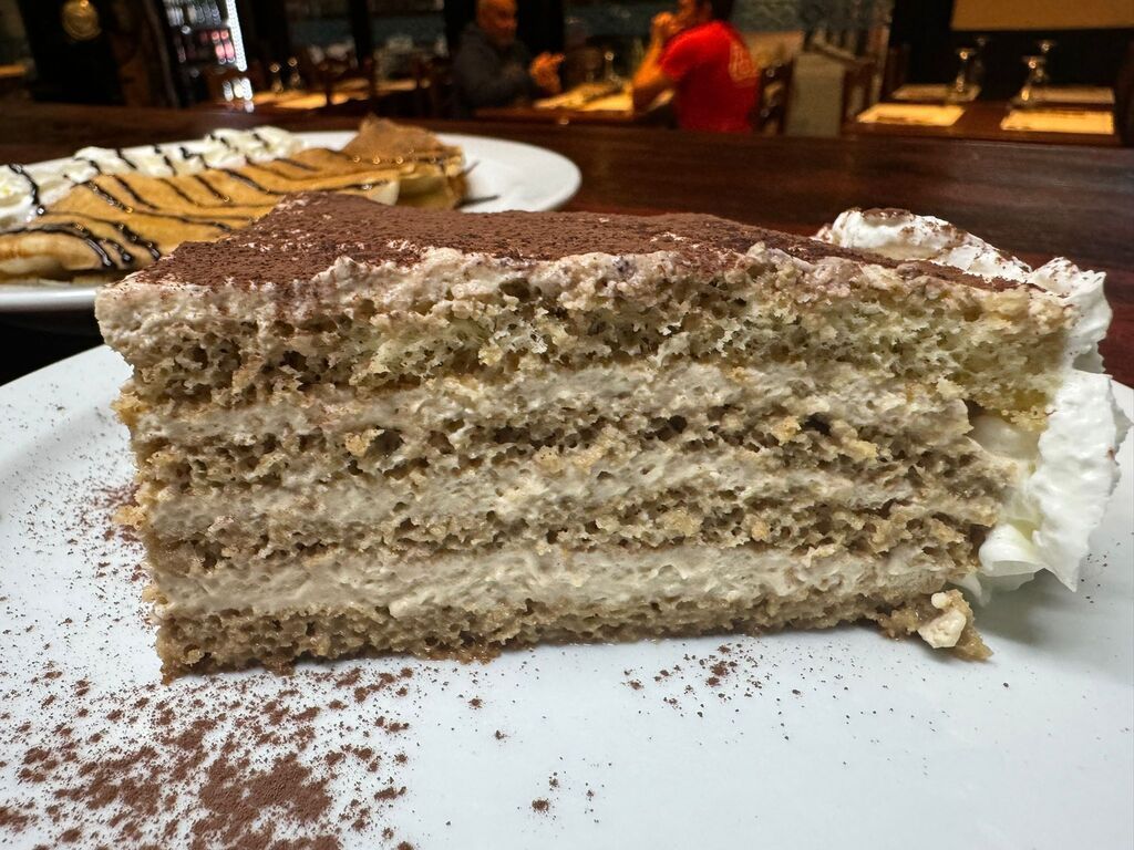 Una rebanada de pastel con crema batida en un plato blanco.