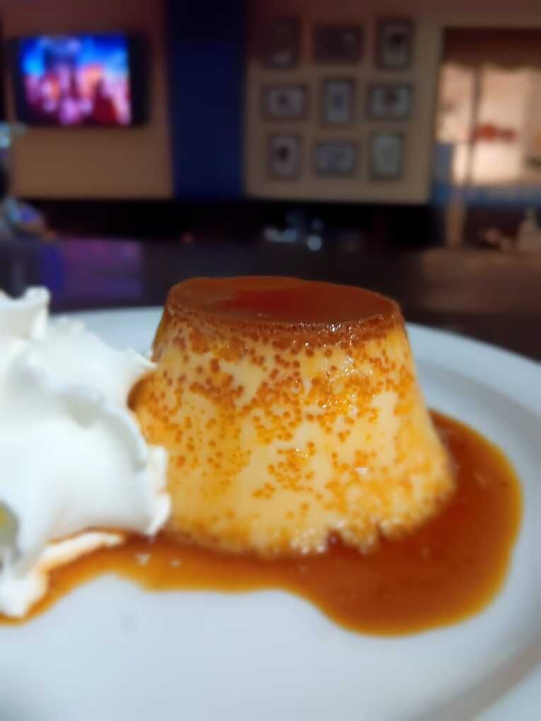 Un plato blanco cubierto con un flan y crema batida.