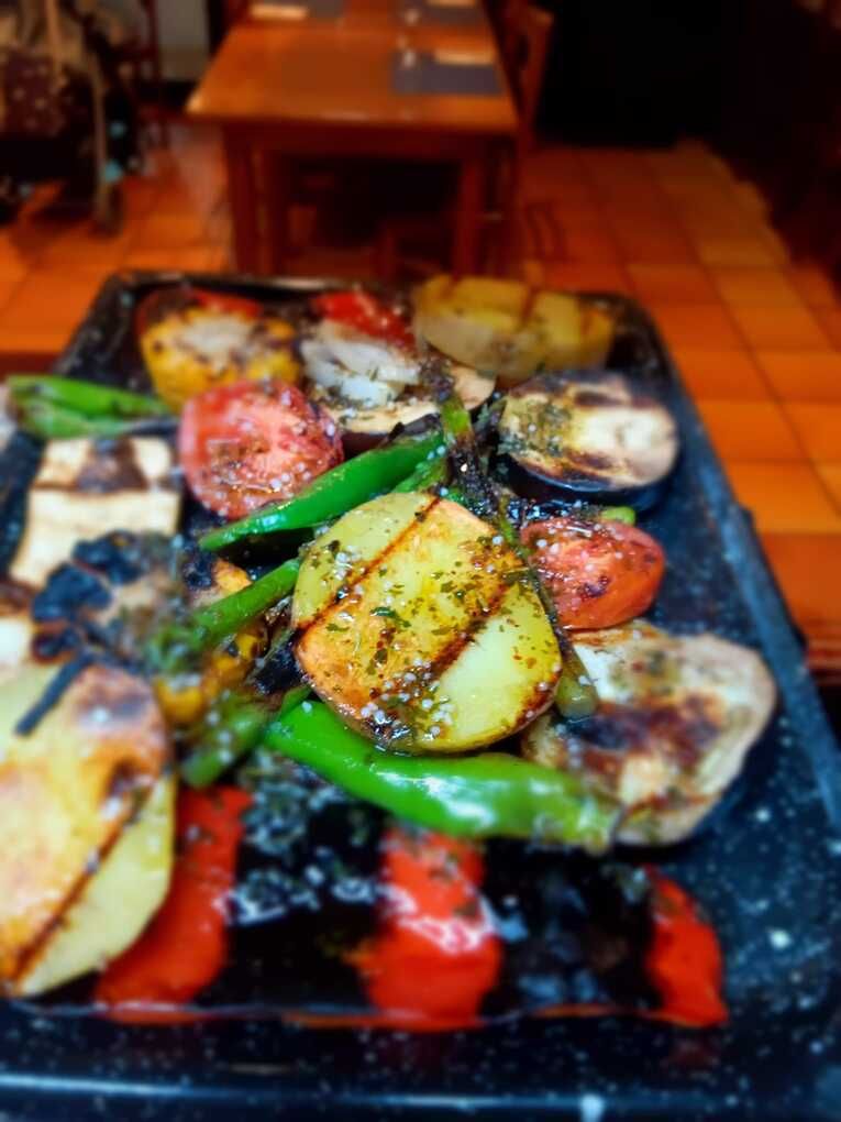 Una bandeja de verduras a la parrilla está sobre una mesa.