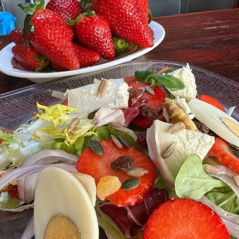 Un plato de fresas se encuentra junto a un plato de ensalada.