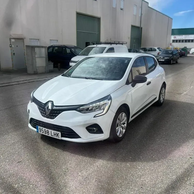 Un coche blanco está aparcado delante de un edificio.